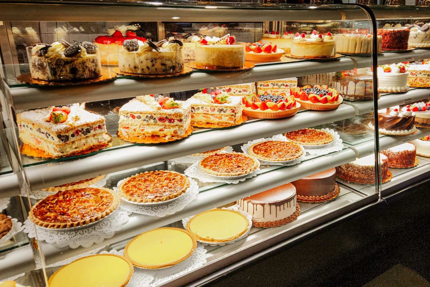Konditorei-Vitrine mit Torten, Obstkuchen und Schnitten in mehreren Etagen